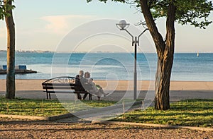 old married couple sit embracing on a bench on the embankment