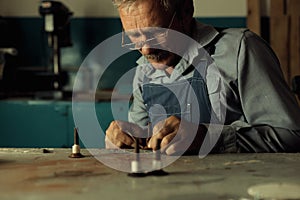 An old master with glasses works in a workshop