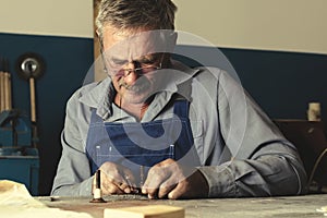 An old master with glasses works in a workshop