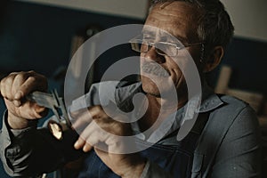 An old master with glasses works in a workshop
