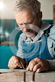 An old master with glasses works in a workshop