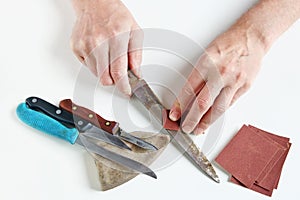 Old master tries to sharpen rusty kitchen knives on his white de