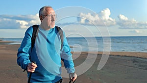 Old mature man backpacker Scandinavian walking stick freedom contemplate sunny sea beach scenery