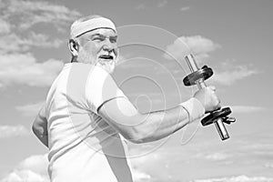 Old mature man exercising with dumbbell. Senior sportsman in sport center. Health club or rehabilitation center for