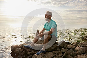 Old mature sportsman enjoying beautiful wild nature after morning jog