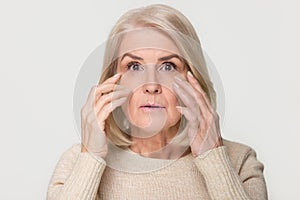Old mature woman looking at camera worried about face wrinkles photo