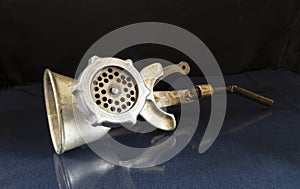 An old meat grinder on a glass table with a reflection