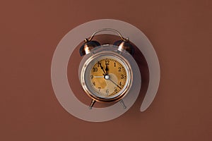 Old mechanical alarm clock on brown background
