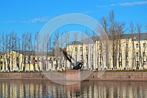 An old mechanical port crane of the XIX century on the shore of the Italian pond on a sunny autumn day in Kronstadt