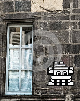 An old medieval building with a window with some modern urban mosaic art