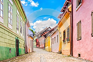 Old medieval cobblestone stree with colorful houses in Sighisoara, Transylvania, Romania