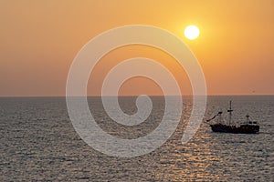 Old medieval sailing ship in sunset on the open sea