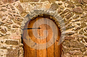 An old, medieval wooden door in a wall of bricks