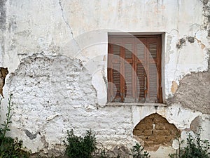 Old Mediterranean house outer wall with window, closed shutters with peeling paint