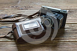 The old medium format rangefinder camera and leather case. Wooden background.