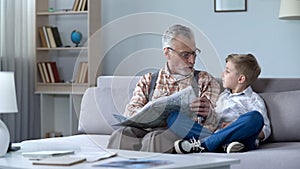 Old man veteran viewing map with grandson showing front line, remembering war photo