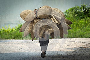 Old men are walking for selling wicker craftsman making traditional bamboo fish trap or weave in Hanoi, Vietnam