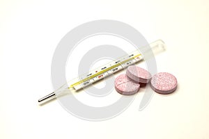 Old mercury medical thermometer with pills closeup on white background