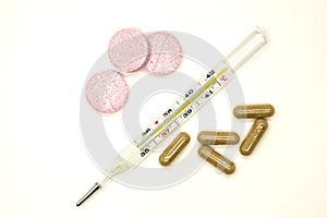 Old mercury medical thermometer with pills closeup on white background