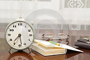 Old metal alarm clock, glasses, book, wallet on the table near t