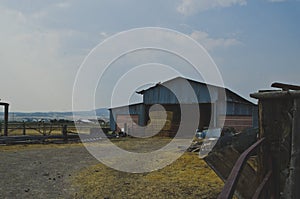 The old metal barn full of hay on the rusty barn under the dusty sky