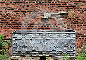 Old metal box in front of weathered brick wall