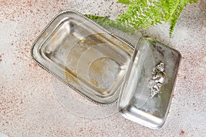 Old metal butter dish and green plant
