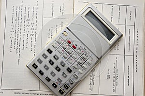 An old metal calculator on the math reference book