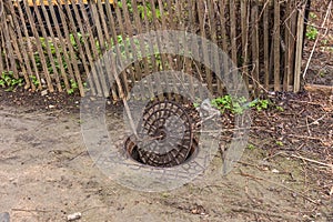 Old metal cast iron canal hatch. Dangerous open unsecured hatch on the road. A broken iron manhole cover opened dangerously in