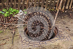 Old metal cast iron canal hatch. Dangerous open unsecured hatch on the road. A broken iron manhole cover opened dangerously in