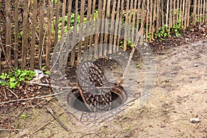 Old metal cast iron canal hatch. Dangerous open unsecured hatch on the road. A broken iron manhole cover opened dangerously in