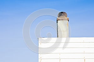 Old metal chimney on the roof of a wooden house - image with cop