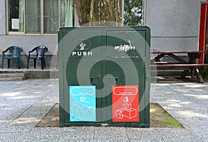 Old metal dark green bins located in a public place for different garbage recycling and general trash