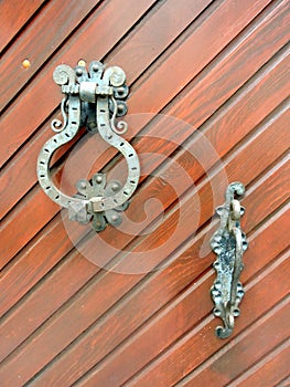 Old metal door knocker and handle for opening an wooden gate - detail