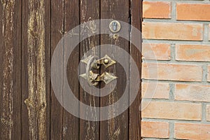 Old metal doorknob on a wooden brown door