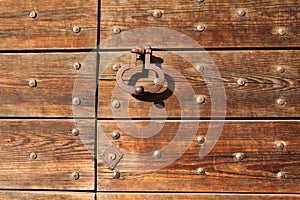 Old metal doorknocker on the wooden gate fixed with rivets