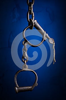 Old metal Handcuffs isolated on a blue textured background