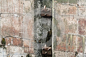 Old metal hooks on the concrete wall of a river sluice.