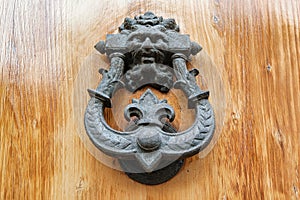 Old metal knocker with satyrs head on a wooden door