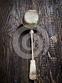 Old metal ladle on the dark wooden background, top view