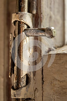 Old metal lock on a white wooden window frame. Old wooden window frame with a small rusty lock.