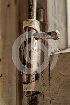 Old metal lock on a white wooden window frame. Old wooden window frame with a small rusty lock.