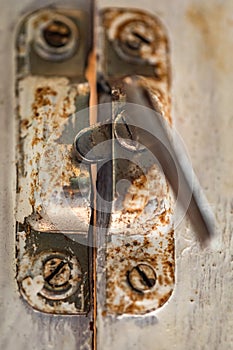 Old metal lock on a white wooden window frame. Old wooden window frame with a small rusty lock.