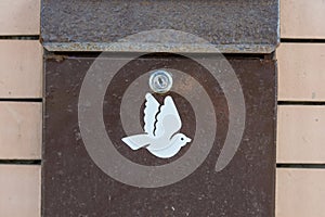 Old metal mailbox with dove symbol hangs on wall