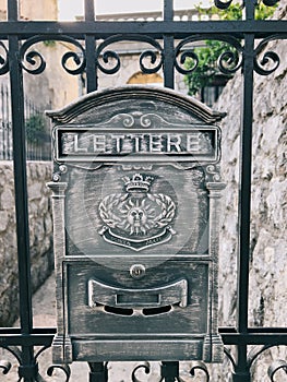 Old metal mailbox hangs on the fence. Caption: Lettere