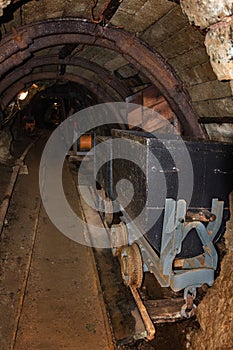 Old metal mine train with rusty wheels in mine tunnel with wooden timbering
