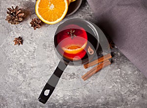 Old metal pan pot of tasty mulled wine with pot with spices and orange fruits on wooden table. Top view