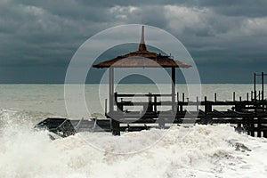 Old metal pier on a beach during a stormy sea