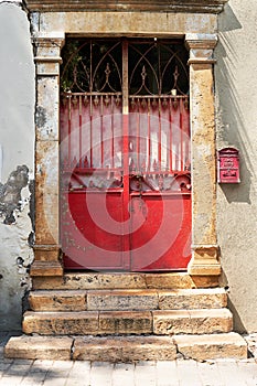 Old metal red doors with stone steps and columns