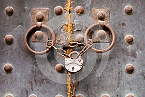 Old metal rusty medieval door locked with a chain and padlock